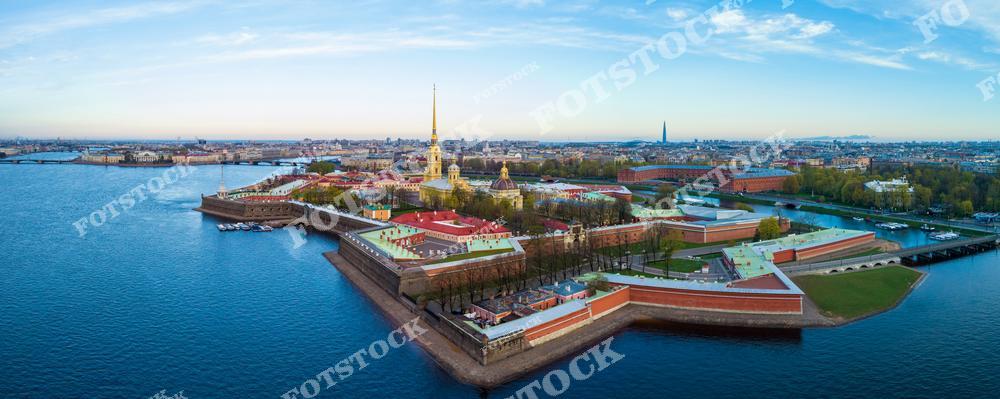 На фото изображена Петропавловская крепость, основанная в 1703 году Петром Великим и являющаяся одним из символов города. В центре возвышается Петропавловский собор с его золотым шпилем, видимым практически с любой точки города. Река Нева окружает крепость, довершая уникальный пейзаж утреннего Санкт-Петербурга.